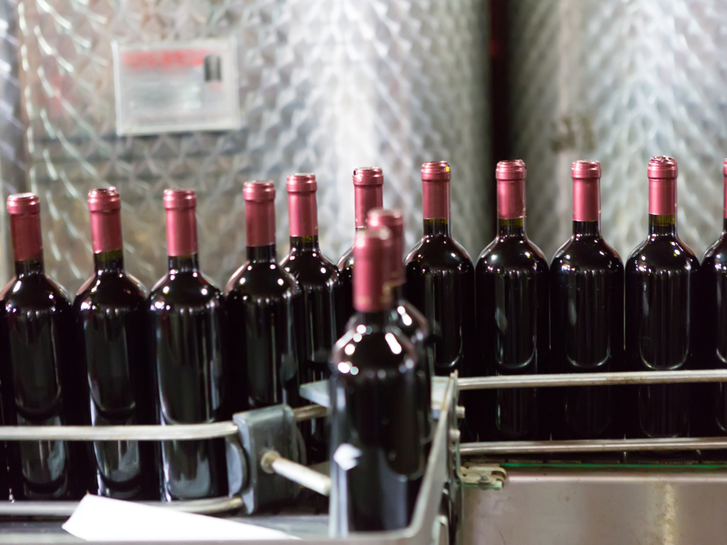 Red wine bottles moving along a winery bottling line after filtration